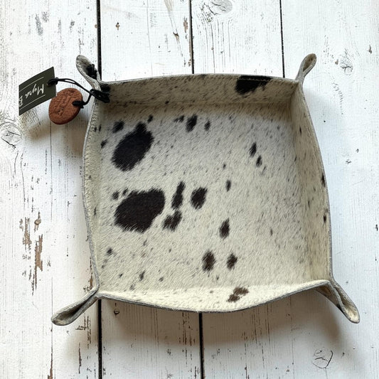 Square tray with black speckles on a white wooden surface, featuring a brand tag.