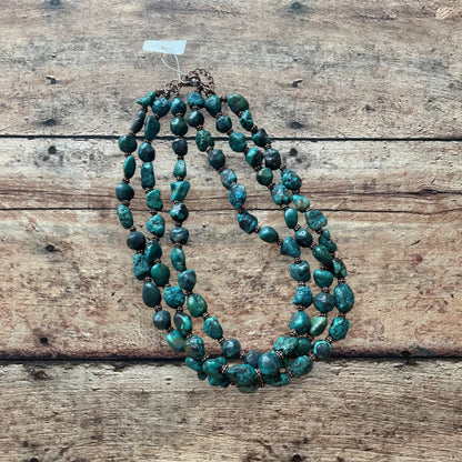 turquoise nugget style beaded necklace on a wooden surface