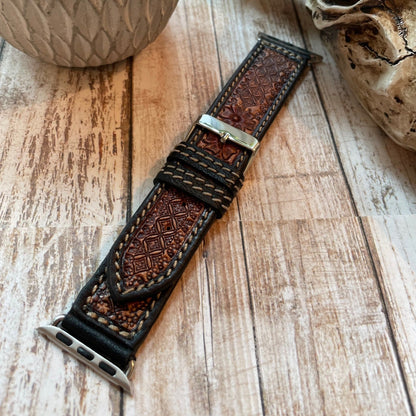 Brown leather watch strap with metal buckle on a wooden surface