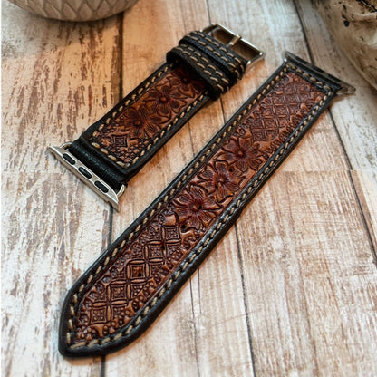 Brown leather watch strap with intricate patterns on a wooden surface