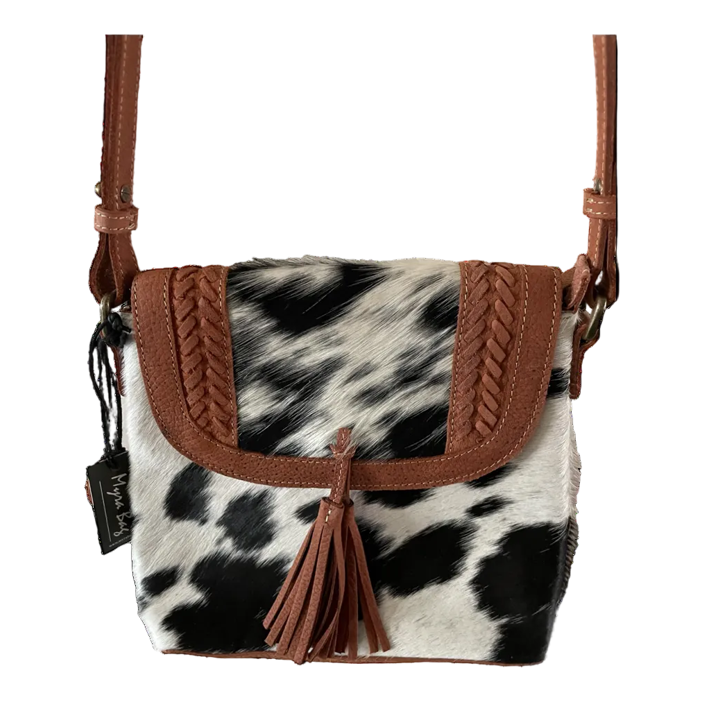 Cow print handbag with brown leather accents on a white background