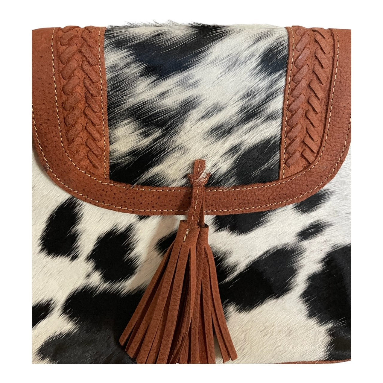 Clutch bag with cow print and brown leather accents on a white background