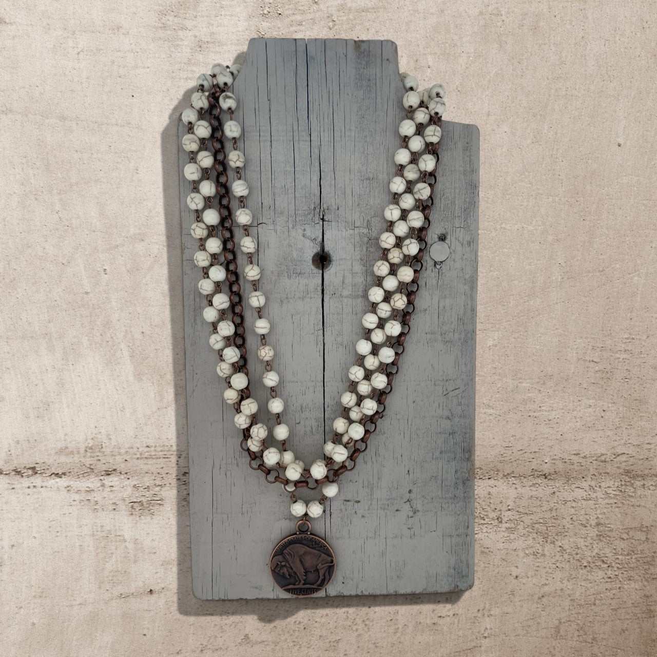 Necklace with white beads and a brown pendant on a wooden board